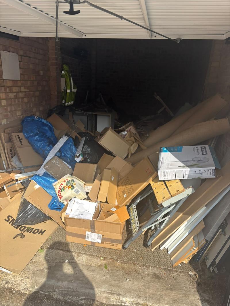 Cardboard, bags and loose contents filling a garage before clearance