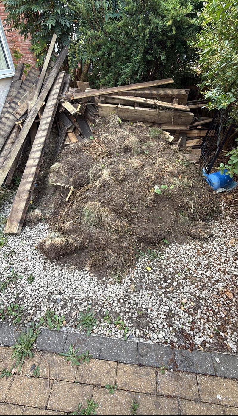 Timber and turf piled beside a house before clearance